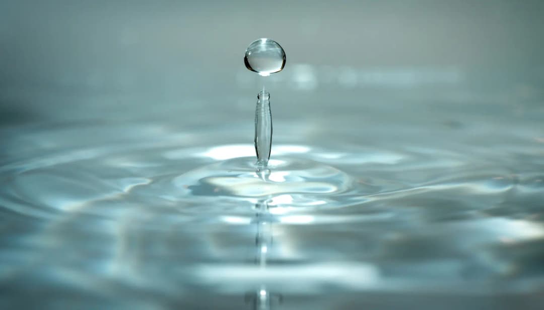 Wassertropfen fällt in eine ruhige Wasseroberfläche