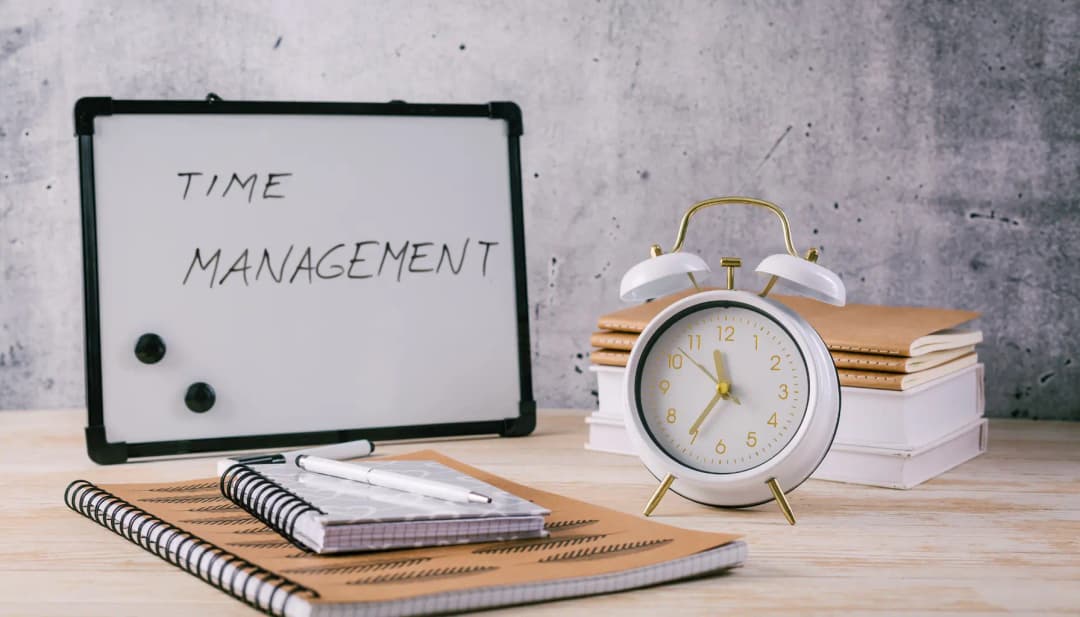 Tafel „Time Management“ neben Wecker und Notizbüchern
