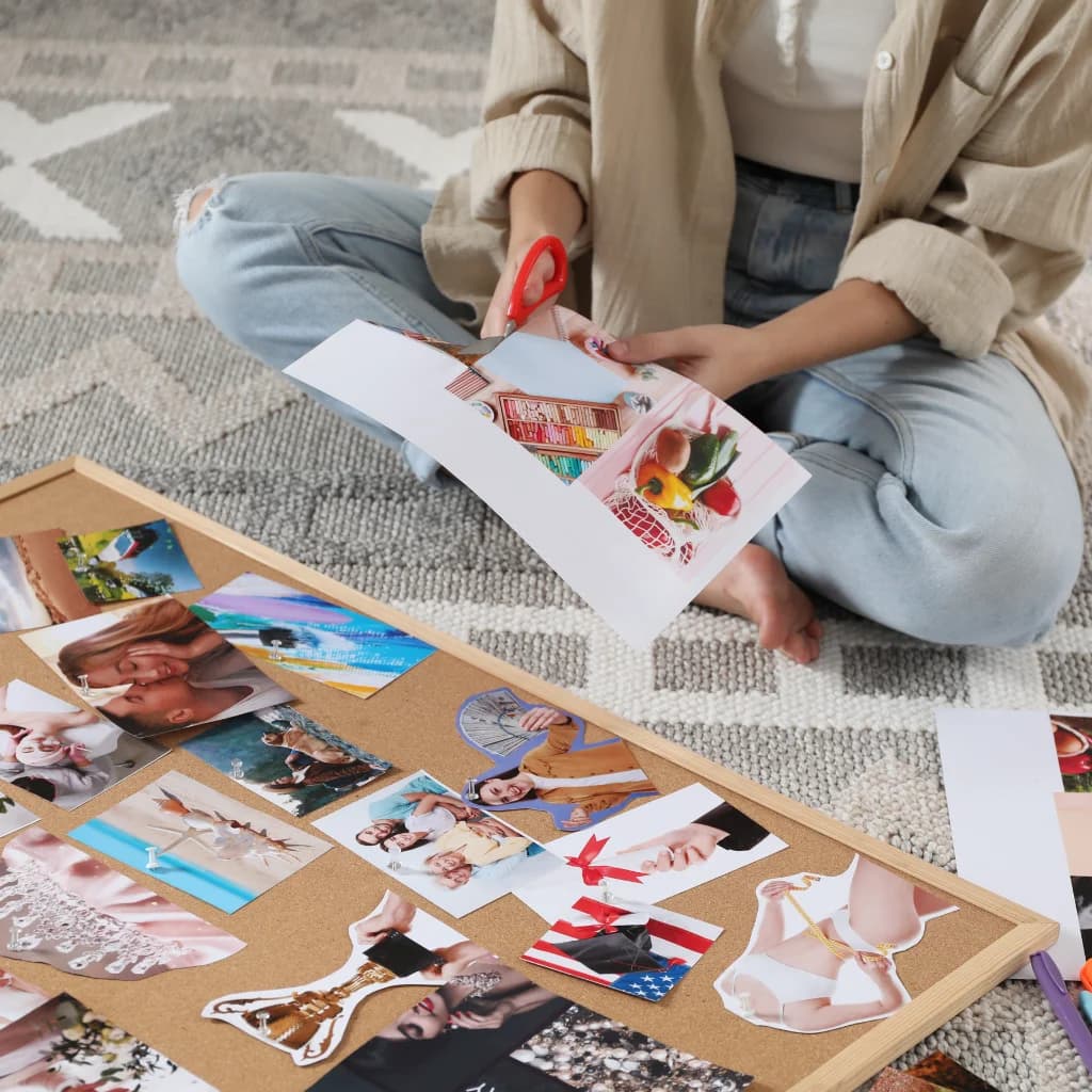 Frau sitzt auf dem Boden und schneidet Bilder für ein Visionboard aus