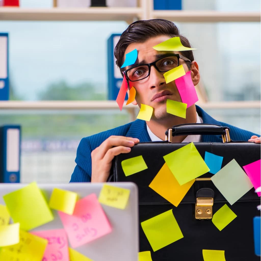 Gestresster Mann im Büro, über und über mit bunten Haftnotizen beklebt