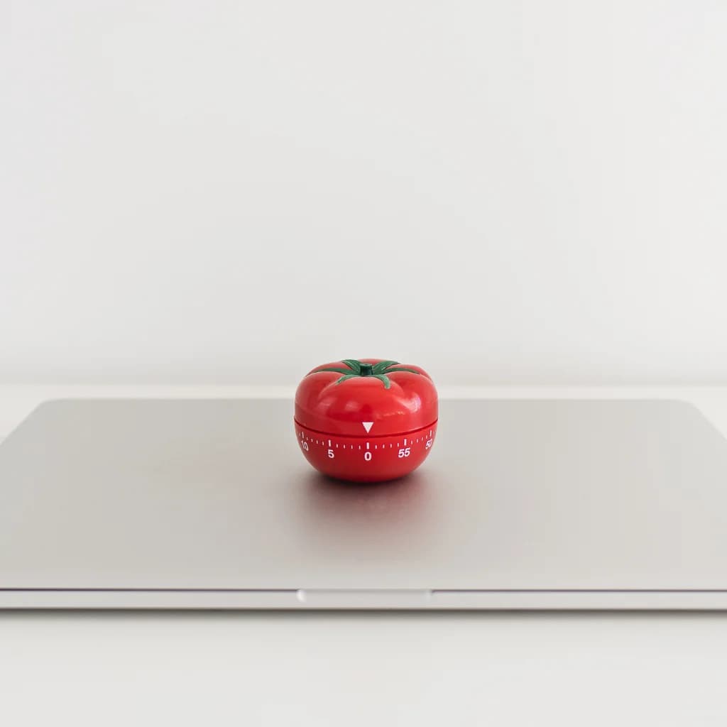 Roter Küchenwecker in Tomatenform auf einem geschlossenen Laptop