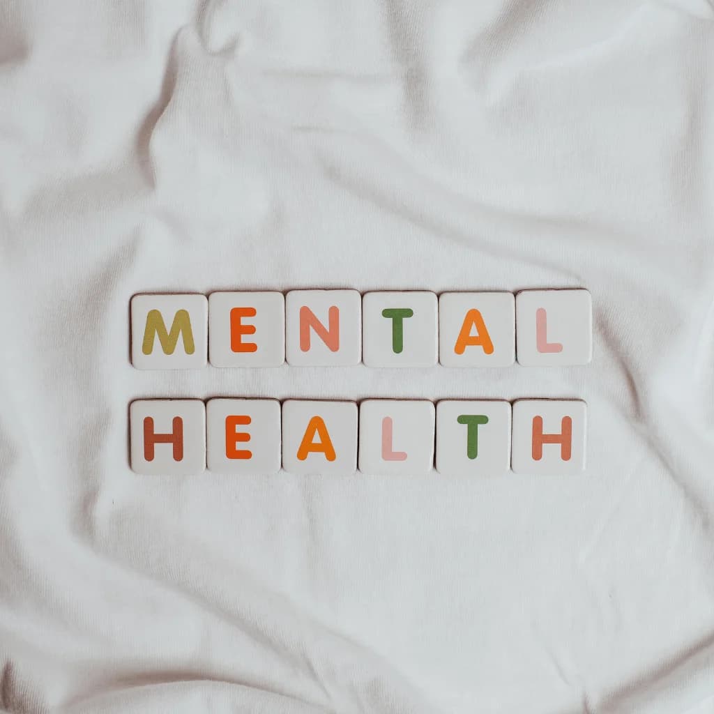 Buchstabenwürfel bilden die Worte „Mental Health“ auf hellem Stoff