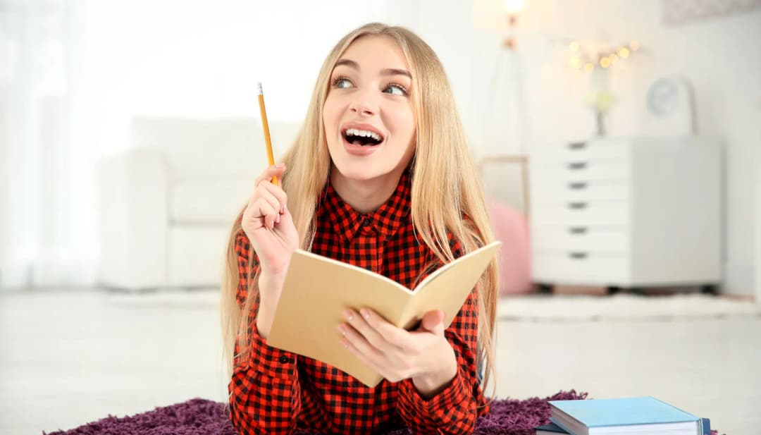 Fröhliche junge Frau mit Notizbuch und Bleistift hat eine Idee