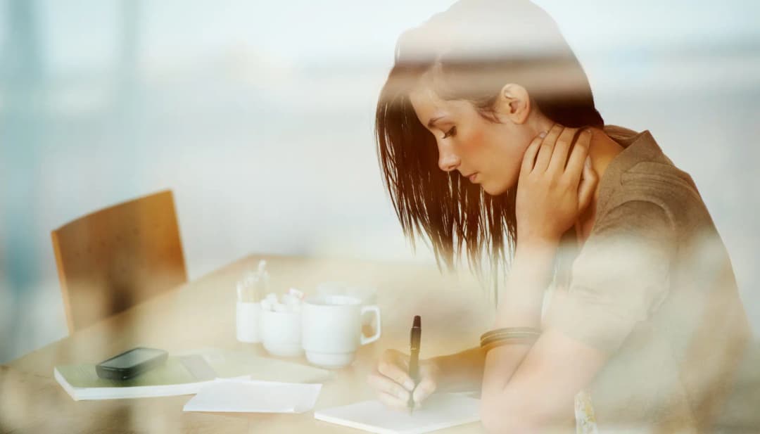 Nachdenkliche Frau am Schreibtisch mit Notizen und Kaffeetassen