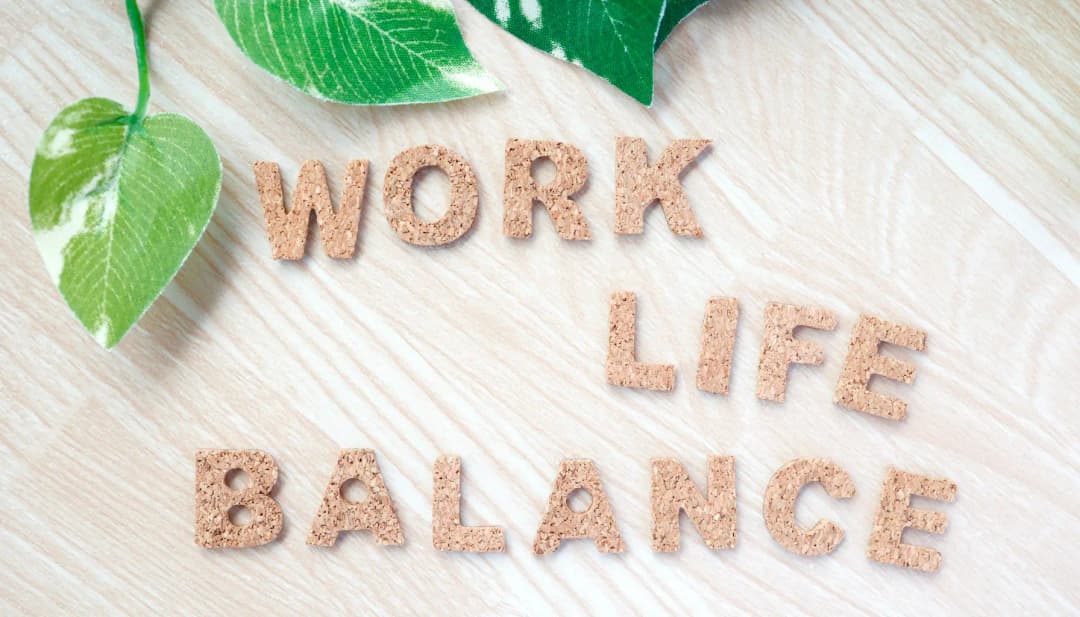 Schriftzug „Work Life Balance“ aus Korkbuchstaben mit grünen Blättern
