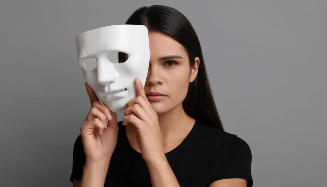 Frau hält eine weiße Maske vor die Hälfte ihres Gesichts